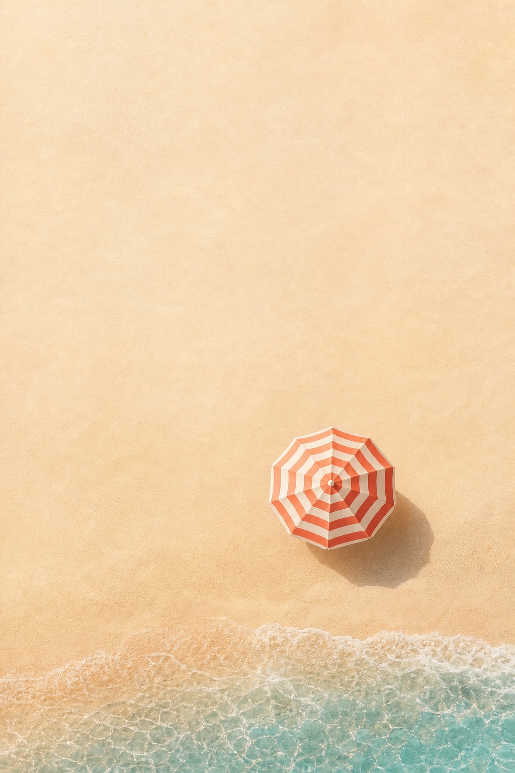 Coral striped beach umbrella on warm sand