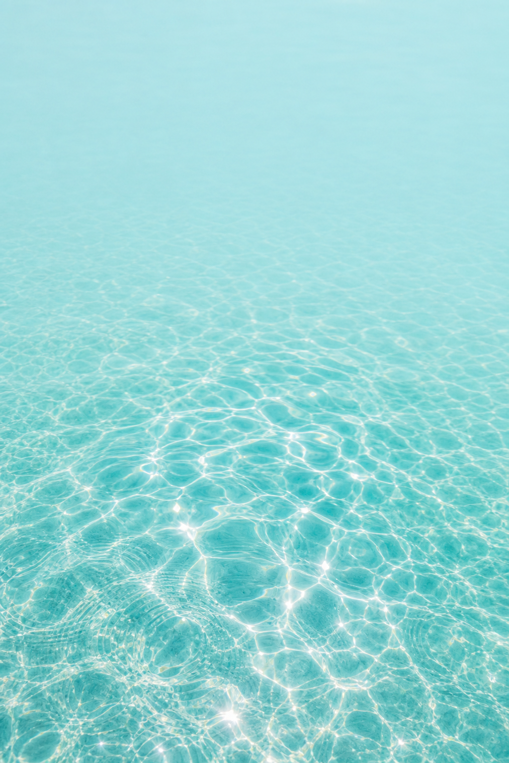 Sunlight ripples on pale aqua pool water